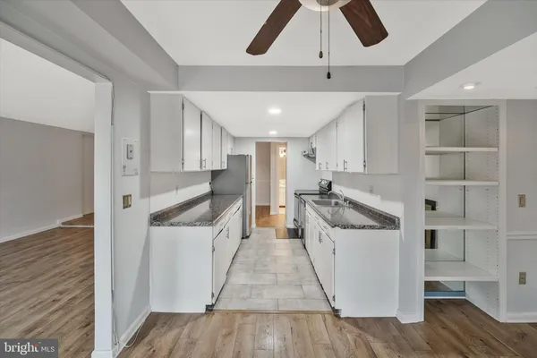 a kitchen with stainless steel appliances kitchen island hardwood floor sink and wooden cabinets
