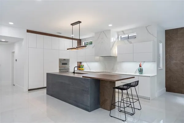a kitchen with kitchen island a dining table chairs cabinets and stainless steel appliances