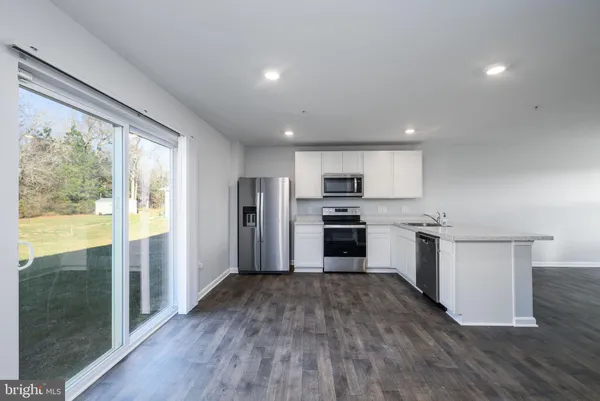 a kitchen with stainless steel appliances a sink a stove a refrigerator cabinets and a dining table