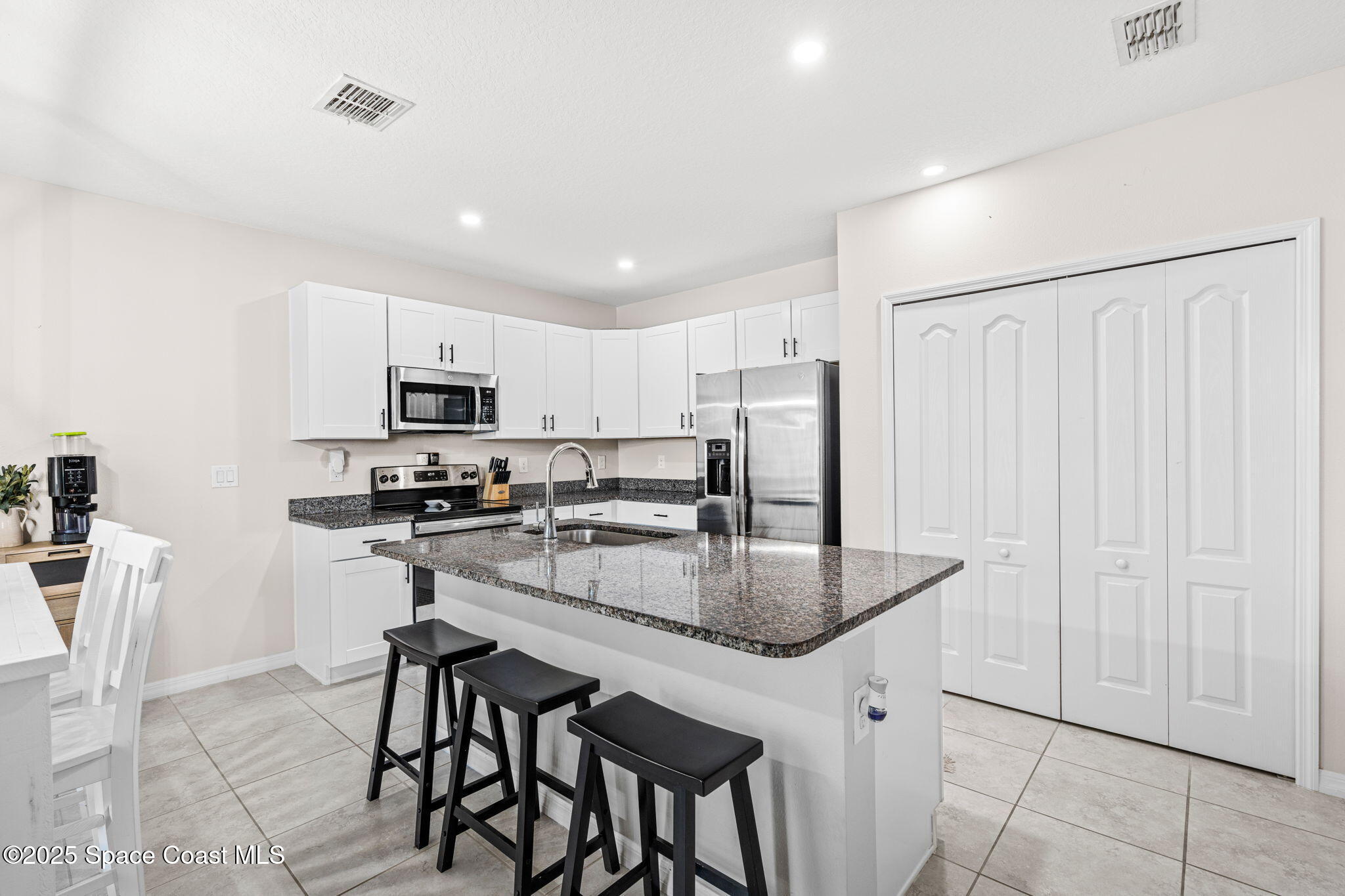 6162 Rena Avenue Cocoa, FL 32927 - Photo 11 of 42 a kitchen with stainless steel appliances granite countertop a stove a refrigerator a sink a table and chairs