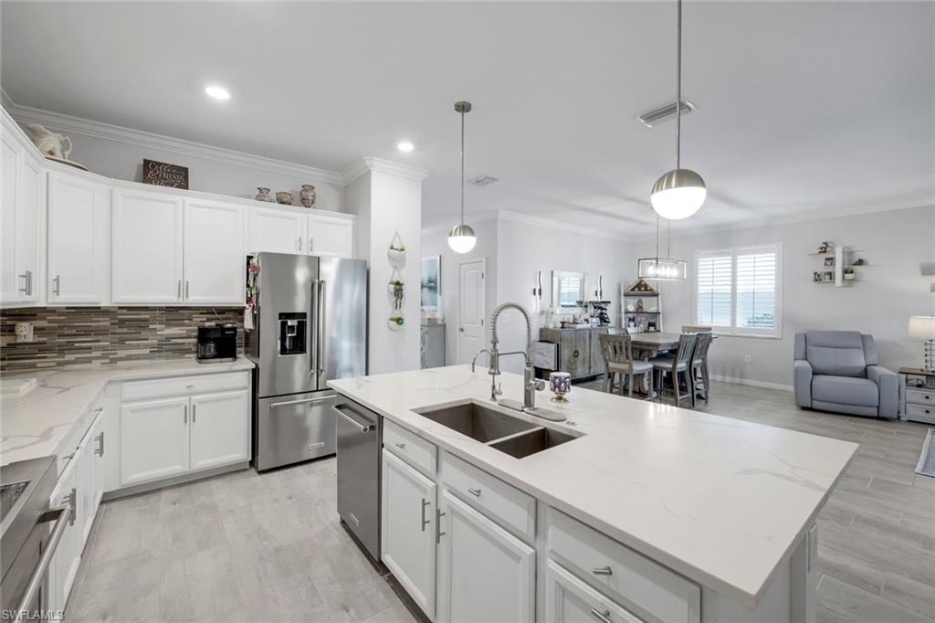 2193 Clementine Street Naples, FL 34120 - Photo 12 of 36 a kitchen with white cabinets and refrigerator