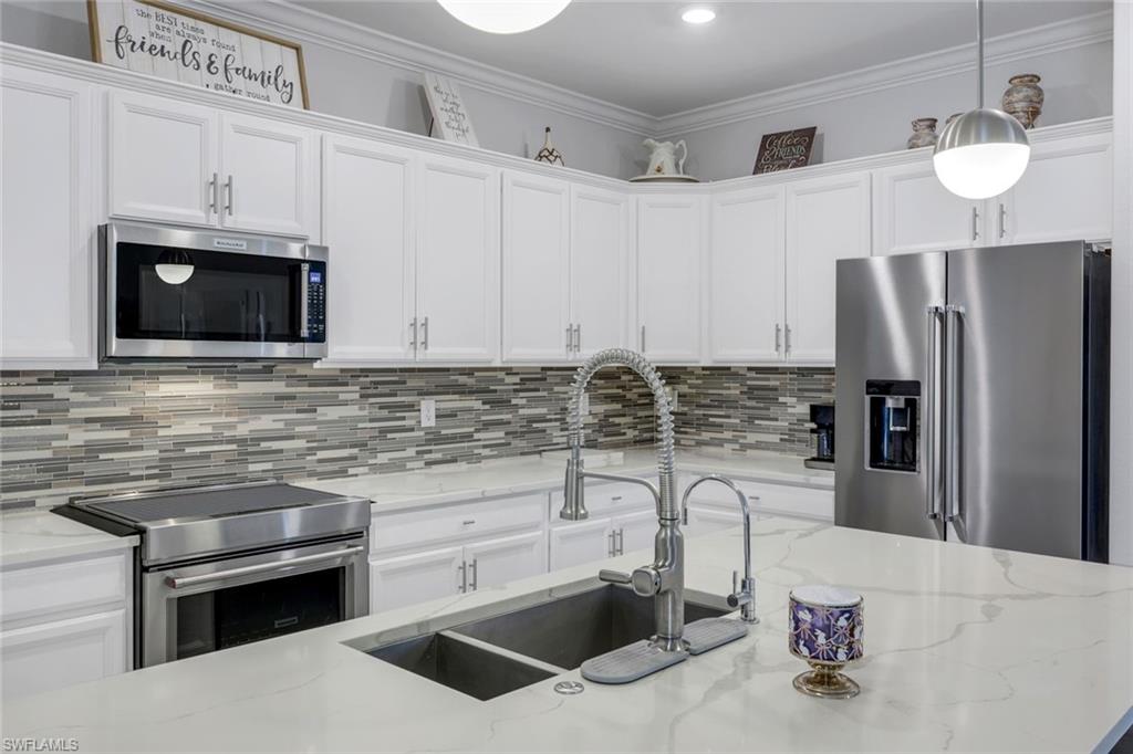 2193 Clementine Street Naples, FL 34120 - Photo 13 of 36 a kitchen with stainless steel appliances a sink a stove a microwave and cabinets