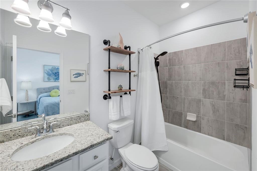 2193 Clementine Street Naples, FL 34120 - Photo 21 of 36 a bathroom with a granite countertop sink toilet a mirror a vanity and bathtub