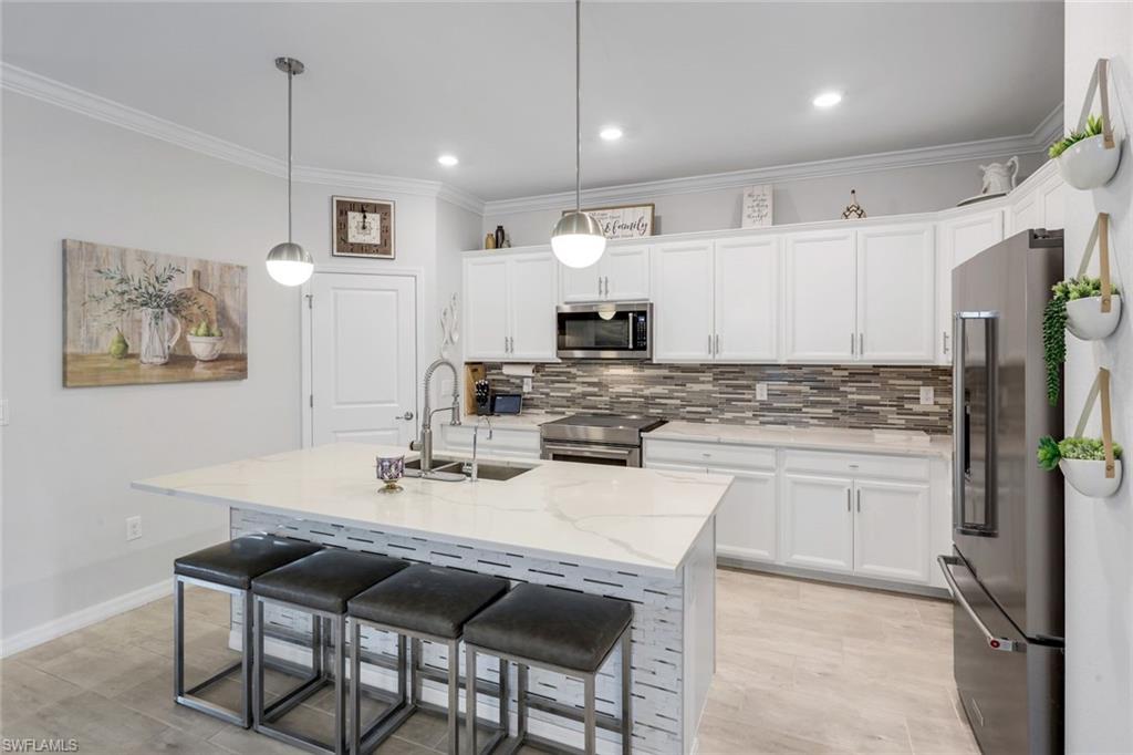 2193 Clementine Street Naples, FL 34120 - Photo 10 of 36 a kitchen with kitchen island granite countertop a sink cabinets and refrigerator