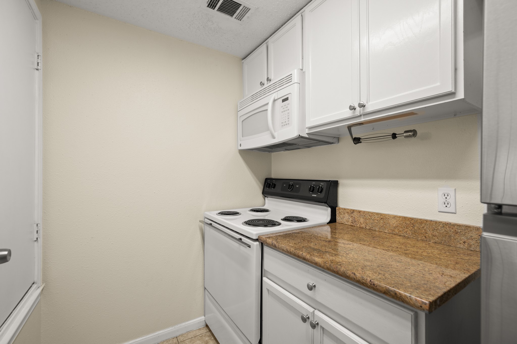 712 West 21st Street, Unit 101 Austin, TX 78705 - Photo 7 of 17 a kitchen with granite countertop white cabinets and a stove with wooden floor