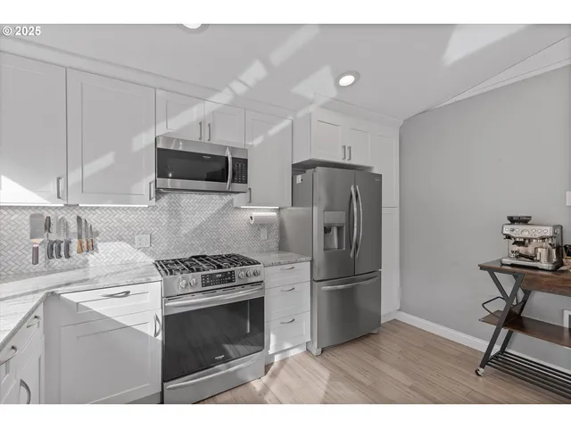 a kitchen with granite countertop a refrigerator stove and microwave