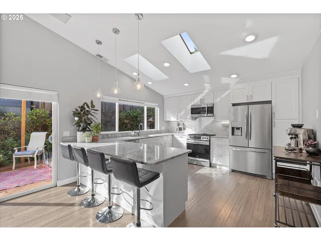 a dining hall with stainless steel appliances kitchen island granite countertop a dining table chairs and granite counter tops