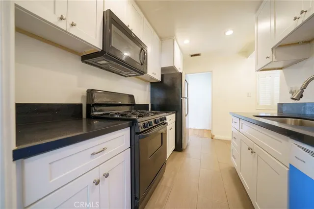 a kitchen with stainless steel appliances granite countertop a stove a sink and a microwave