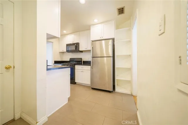 a kitchen with a refrigerator a stove top oven and white cabinets