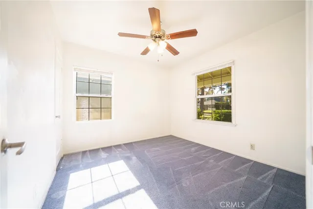 an empty room with windows and fan