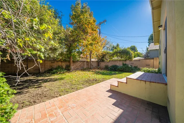 a view of a yard with plants and a wooden fence
