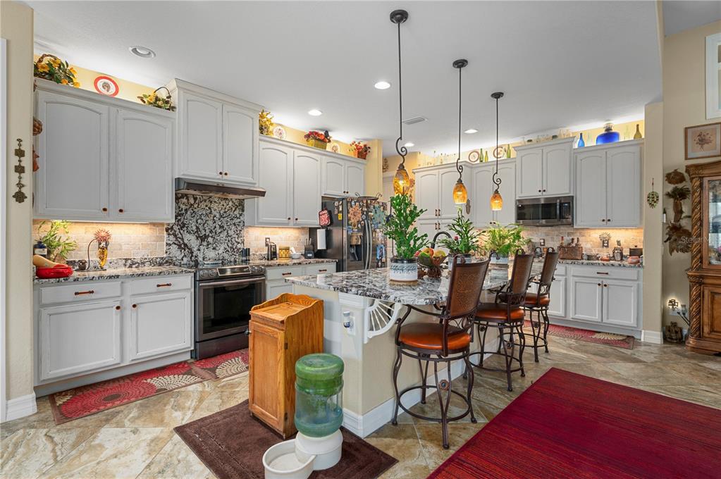 38881 Washington Loop Road Punta Gorda, FL 33982 - Photo 15 of 63 a kitchen with stainless steel appliances kitchen island granite countertop a refrigerator a stove a sink dishwasher and a dining table with wooden floor