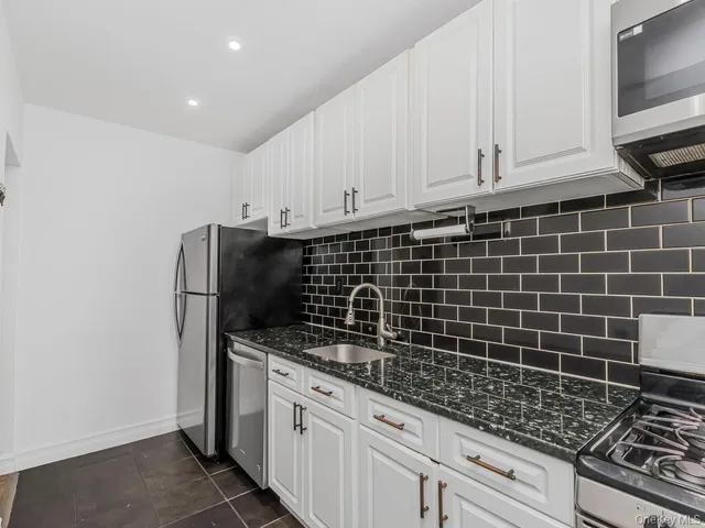 a kitchen with granite countertop a sink stove and cabinets