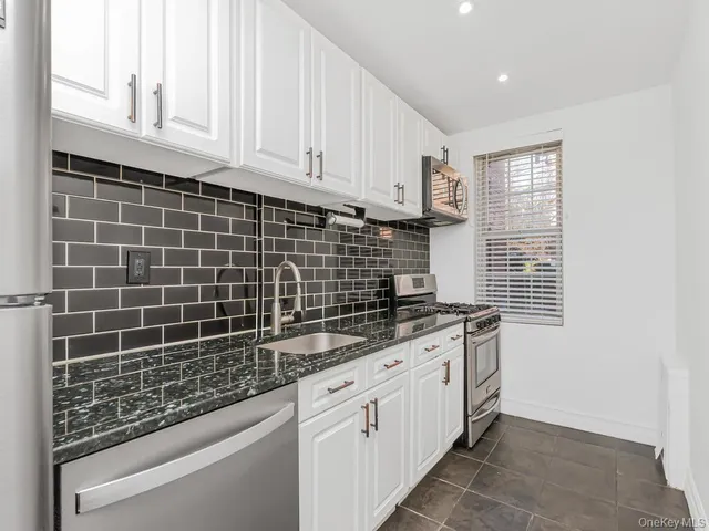 a kitchen with granite countertop a sink a stove and cabinets
