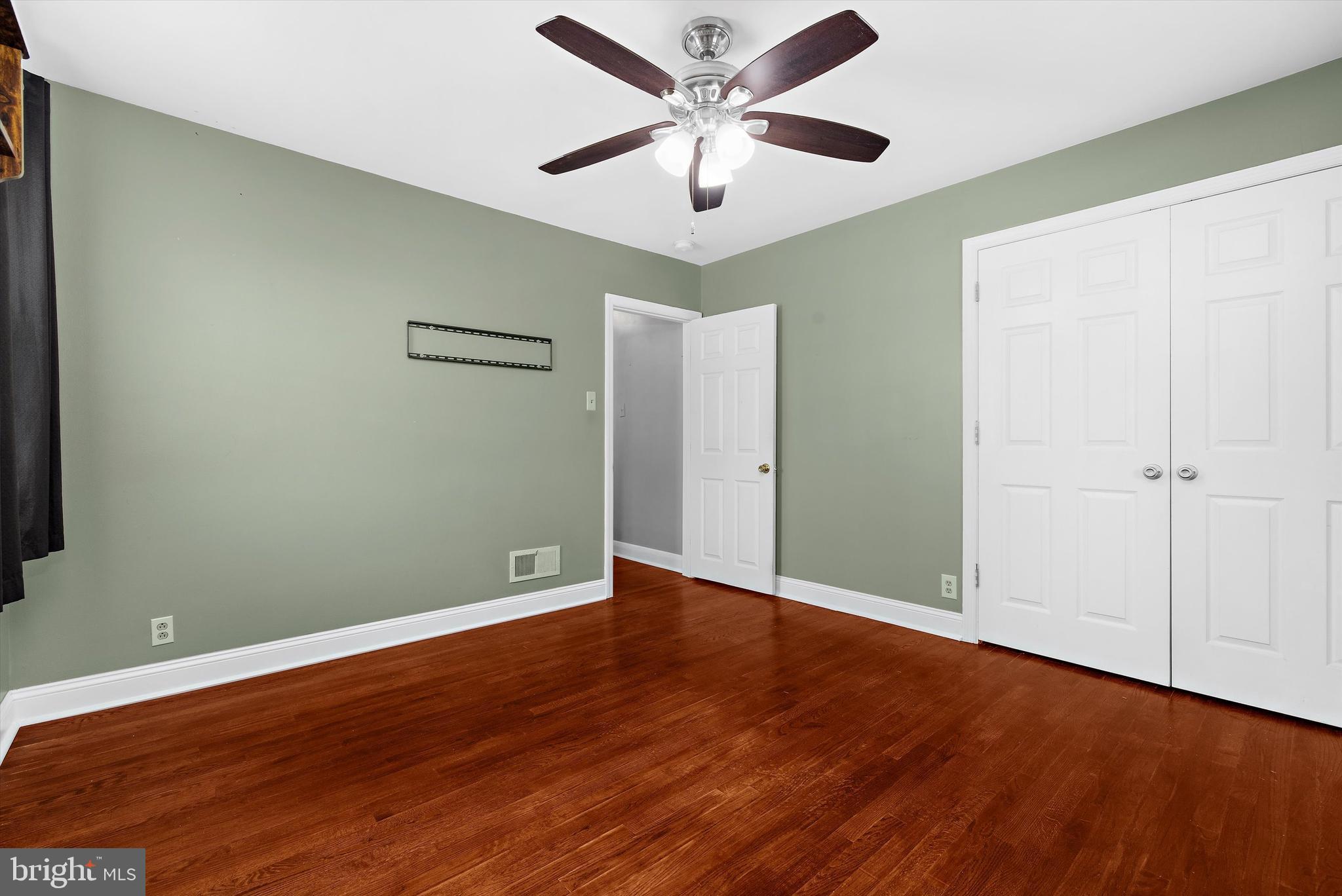 8464 Geneva Road Pasadena, MD 21122 - Photo 17 of 59 an empty room with wooden floor and a ceiling fan