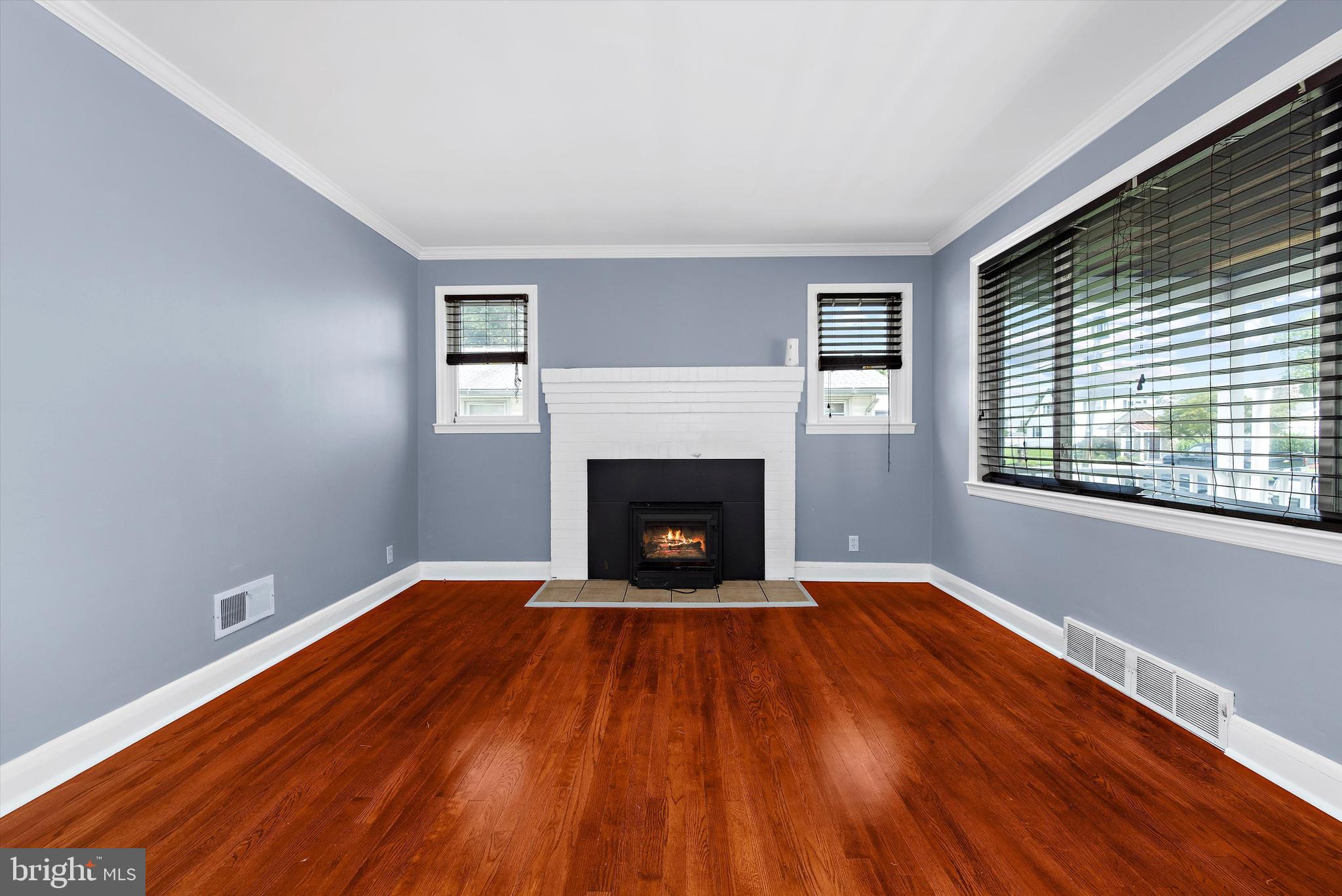 8464 Geneva Road Pasadena, MD 21122 - Photo 6 of 59 a view of an empty room with wooden floor fireplace and a window