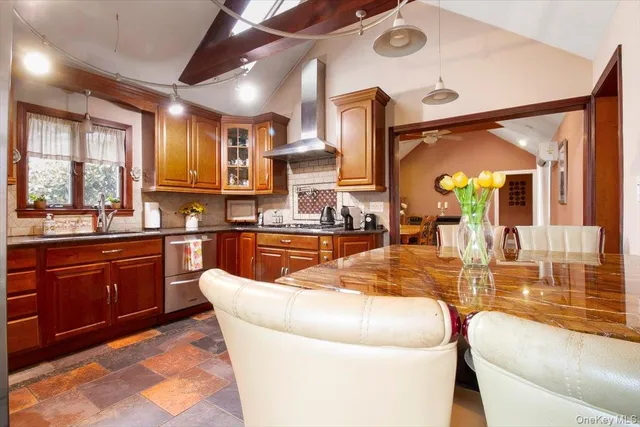 a large kitchen with stainless steel appliances wooden floor and a large window