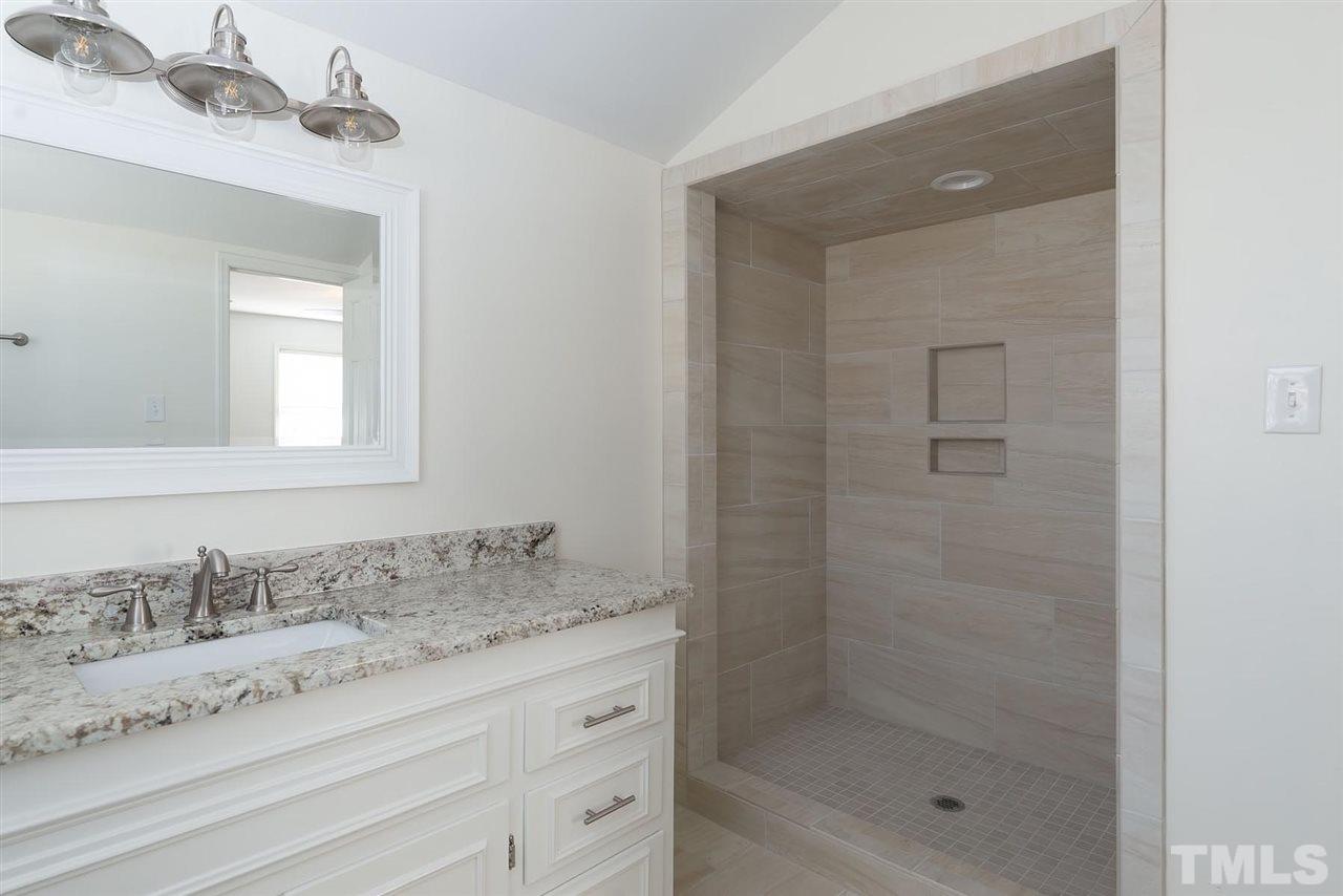 5828 Morning Forest Drive Raleigh, NC 27609 - Photo 17 of 25 a bathroom with a granite countertop sink a mirror and a shower