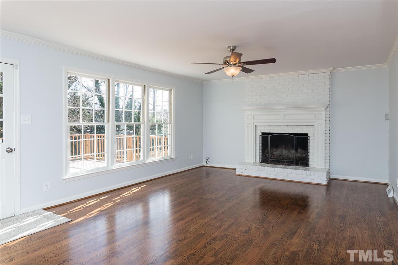 5828 Morning Forest Drive Raleigh, NC 27609 - Photo 6 of 25 a view of an empty room with wooden floor fireplace and a window