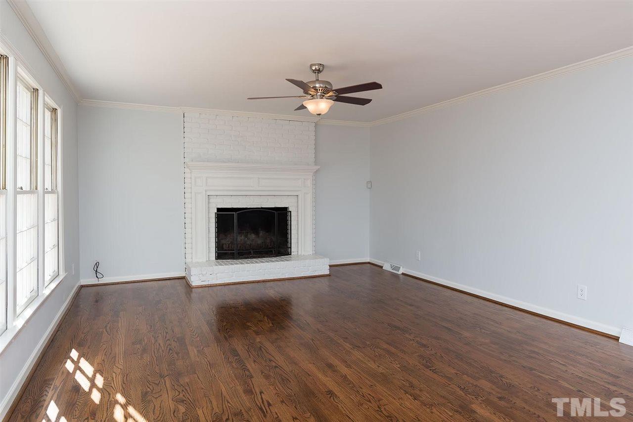 5828 Morning Forest Drive Raleigh, NC 27609 - Photo 7 of 25 an empty room with wooden floor a chandelier fan and windows