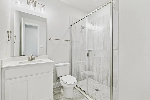 a bathroom with a shower sink vanity mirror and toilet