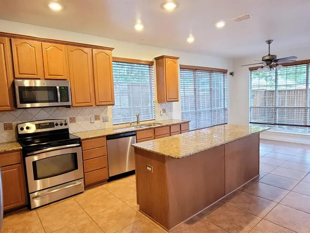 a kitchen with stainless steel appliances granite countertop a stove top oven a sink and a refrigerator