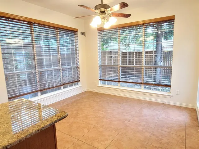 an empty room with wooden floor ceiling fan and windows