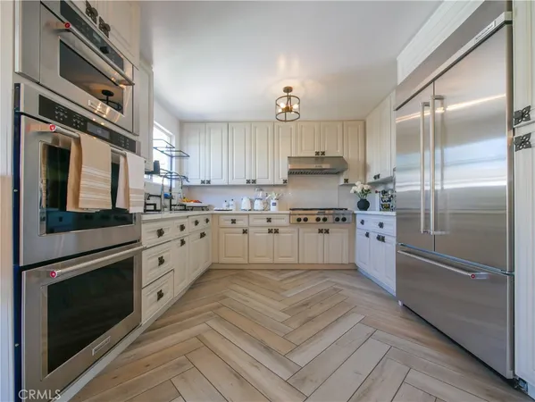 a kitchen with stainless steel appliances granite countertop a refrigerator a stove and a sink with wooden floor