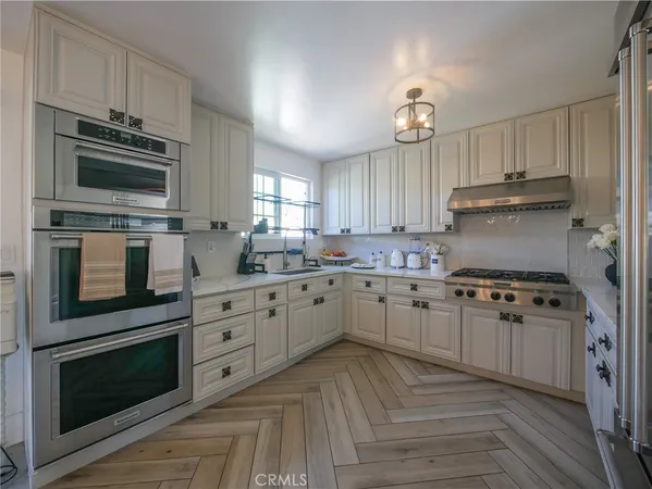 a kitchen with cabinets stainless steel appliances and a window