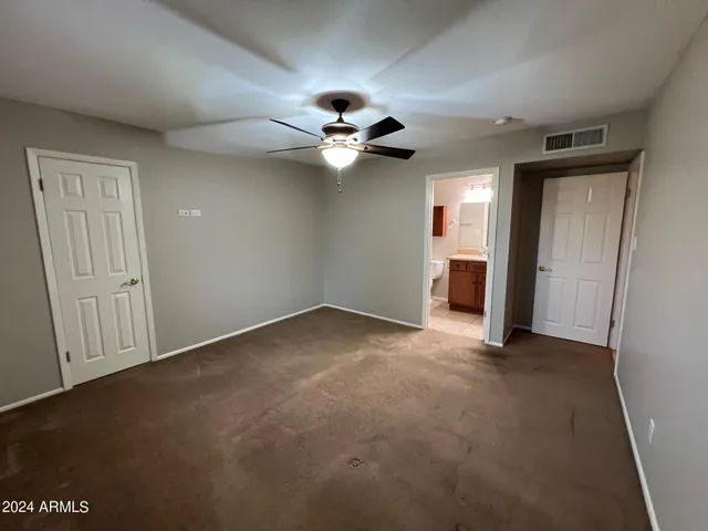 an empty room with closet and a ceiling fan