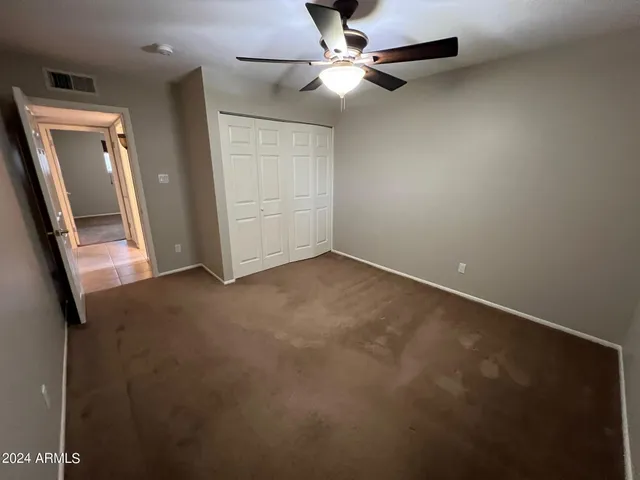 an empty room with windows and fan