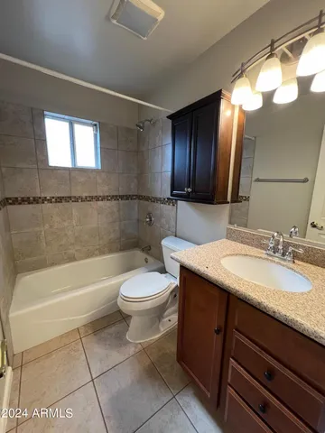 a bathroom with a granite countertop sink mirror vanity bathtub and a toilet