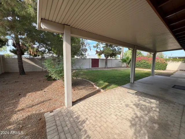 a view of a patio with table and chairs under an umbrella with a big yard