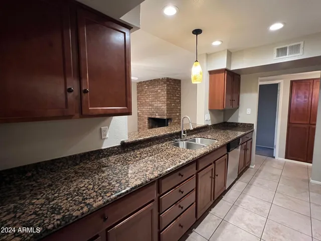 a large kitchen with kitchen island granite countertop a sink a counter space and cabinets
