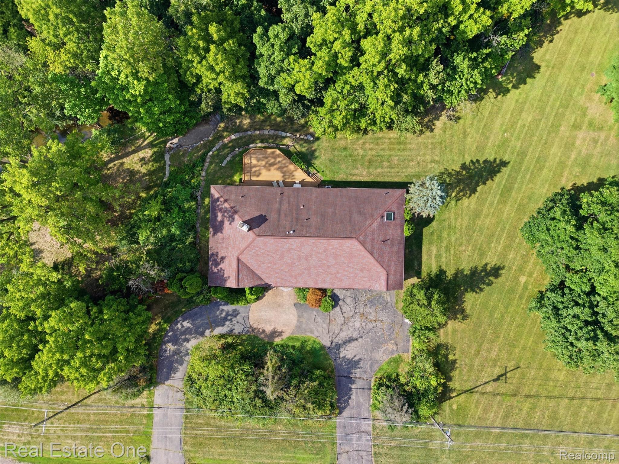 2626 West Wattles Road Troy, MI 48098 - Photo 59 of 65 Gable roofline with a chimney, featuring a surrounding treeline and expansive grassy areas