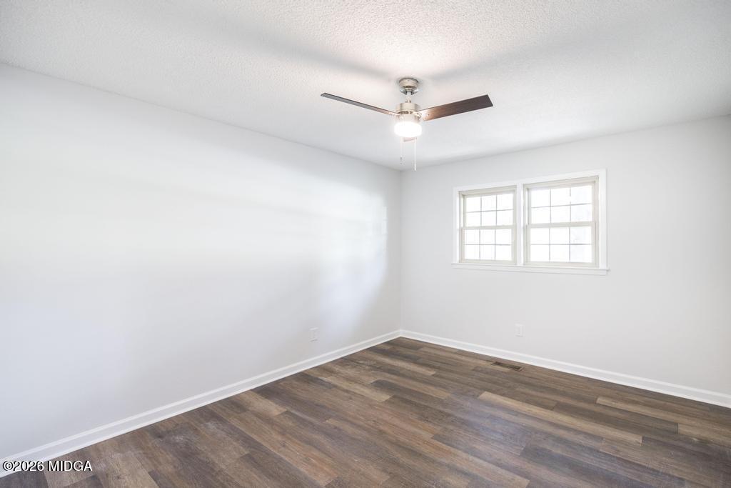 303 Woodhaven Road Centerville, GA 31028 - Photo 22 of 35 an empty room with wooden floor ceiling fan and windows