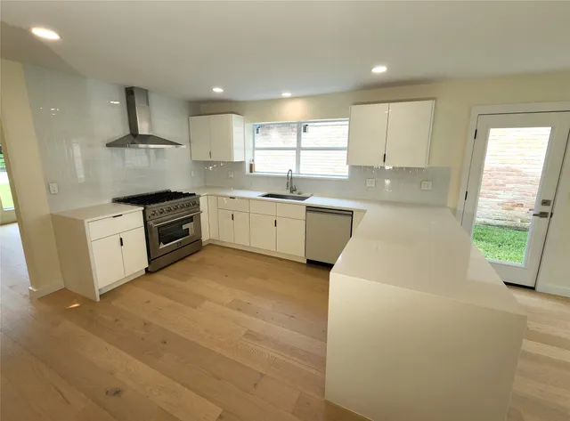 a large kitchen with stainless steel appliances granite countertop a stove a sink and a refrigerator