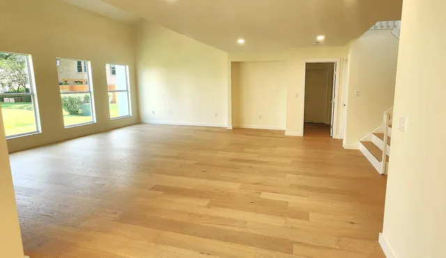 a view of an empty room with a window and wooden floor
