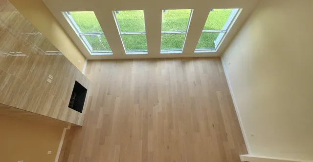 a view of an empty room with wooden floor and a window