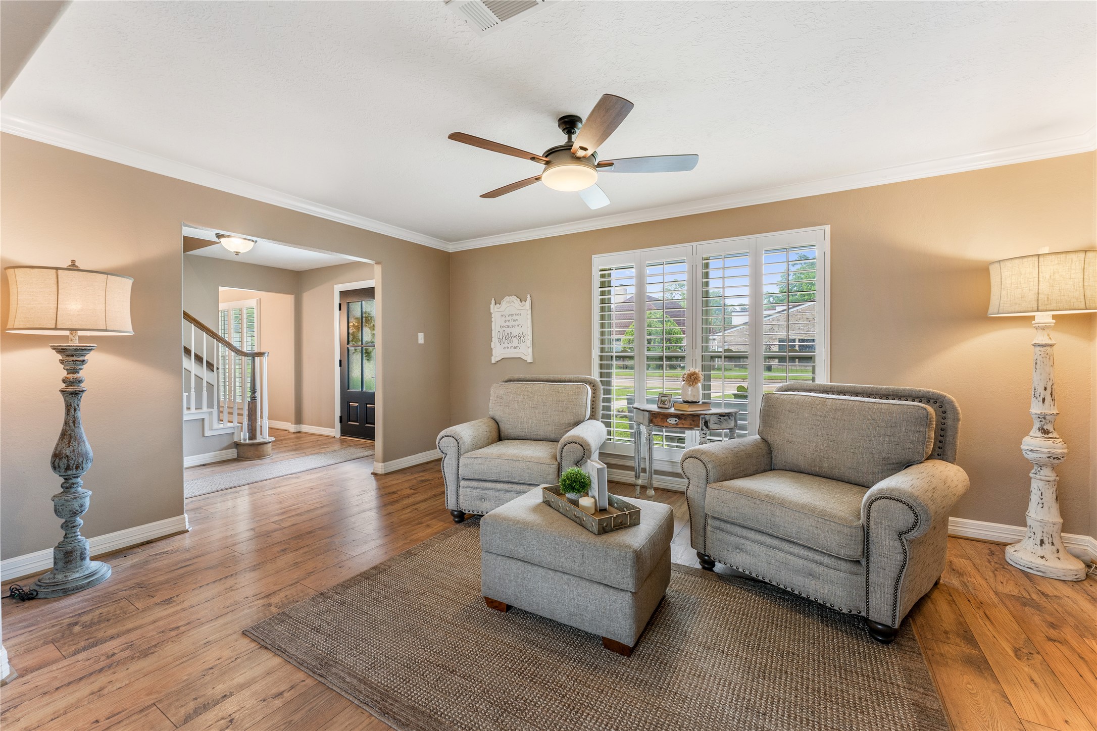 3301 Winter Lane Baytown, TX 77521 - Photo 11 of 28 This cozy family room features neutral walls, creating an inviting atmosphere. Large windows with plantation shutters let in natural light. The space connects seamlessly to the entryway and staircase, enhancing flow.