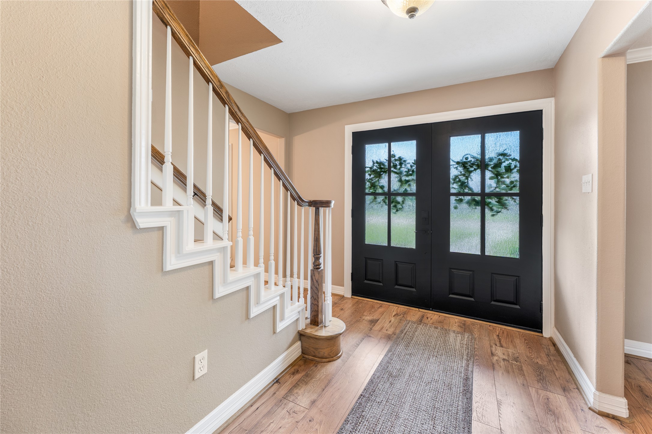 3301 Winter Lane Baytown, TX 77521 - Photo 12 of 28 A welcoming entryway with double black doors, frosted glass, and a warm-toned staircase. Creating an inviting atmosphere.