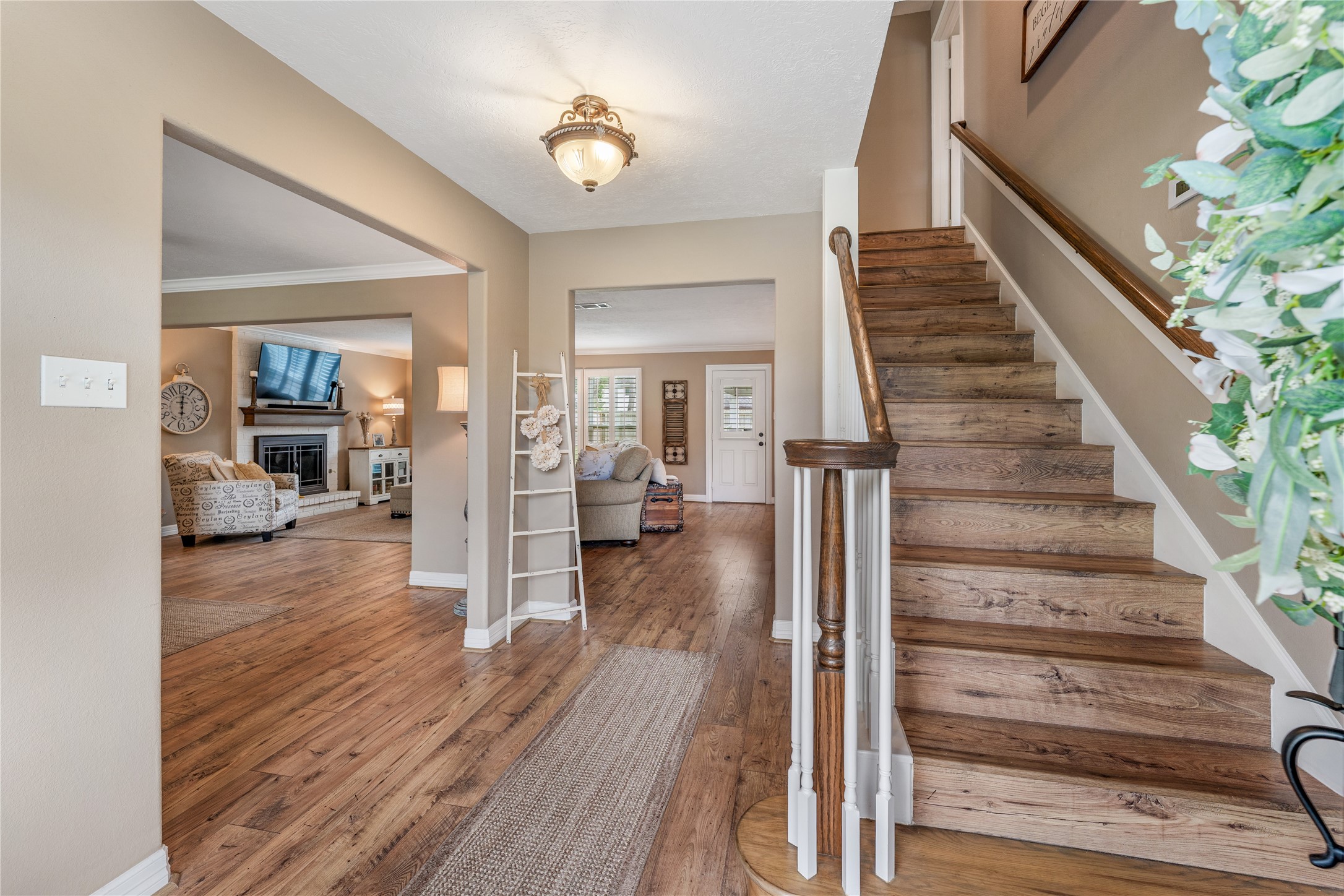 3301 Winter Lane Baytown, TX 77521 - Photo 13 of 28 This welcoming home features a warm, open entryway with beautiful flooring and a staircase leading to the second level. The living area is cozy, with a fireplace and ample natural light, creating an inviting atmosphere.