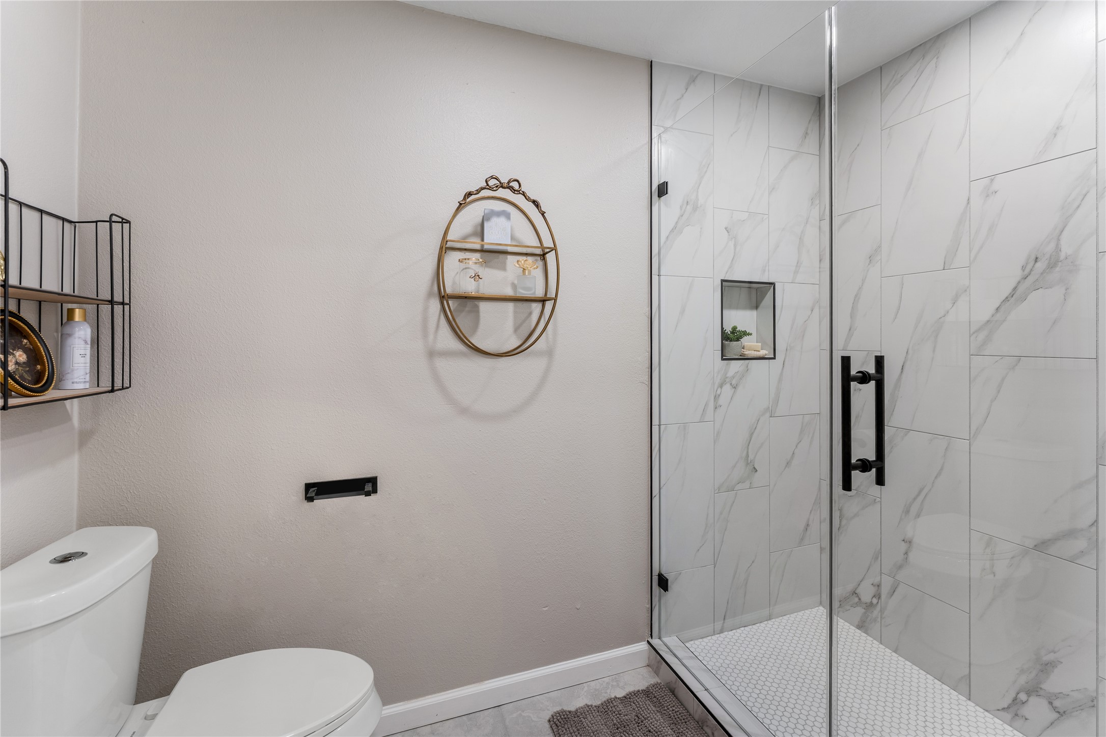 3301 Winter Lane Baytown, TX 77521 - Photo 16 of 28 This bathroom features a modern design with a glass-enclosed shower, tiles, and a sleek wall-mounted shelf for added storage.