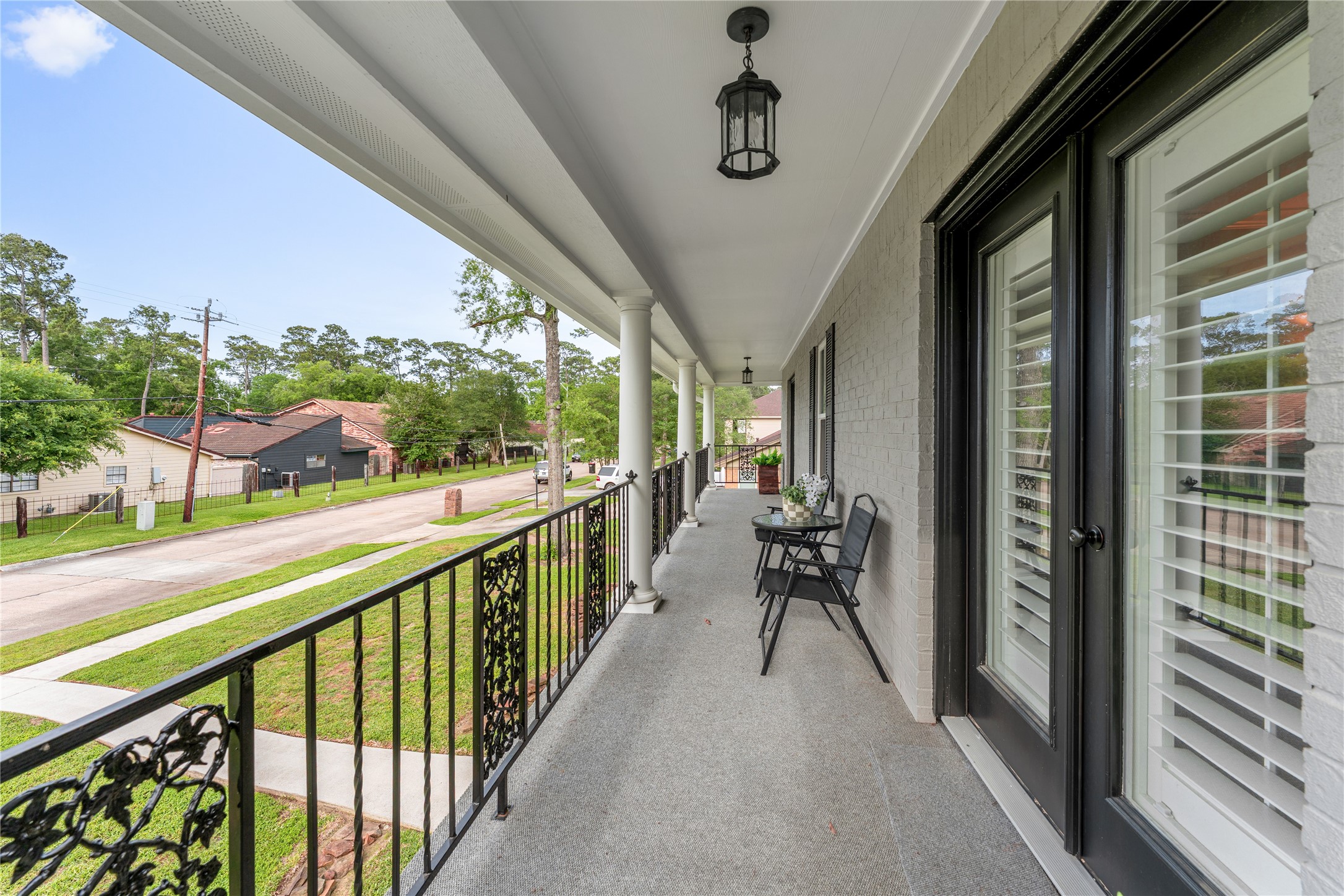 3301 Winter Lane Baytown, TX 77521 - Photo 18 of 28 This is a spacious covered balcony with stylish black railings and light fixtures. It overlooks a well-maintained yard and offers a comfortable outdoor seating area, perfect for relaxation and enjoying the view. Accesible through primary bedroom and through a secondary bedroom.