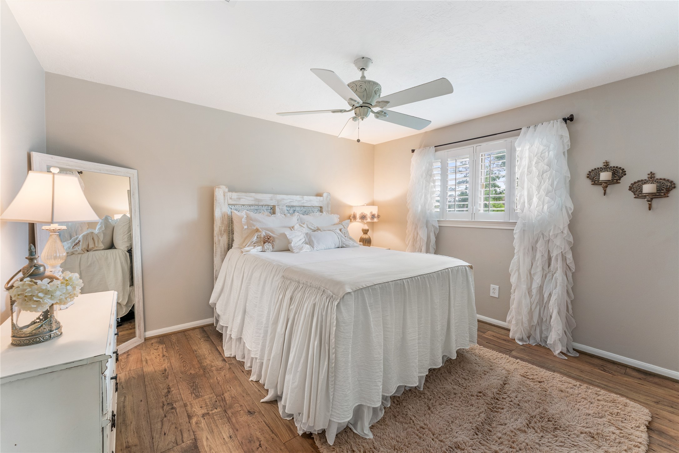 3301 Winter Lane Baytown, TX 77521 - Photo 19 of 28 This cozy bedroom features a soft, neutral color palette with elegant decor. It includes a comfortable bed and a ceiling fan. The room is brightened by natural light from the window.