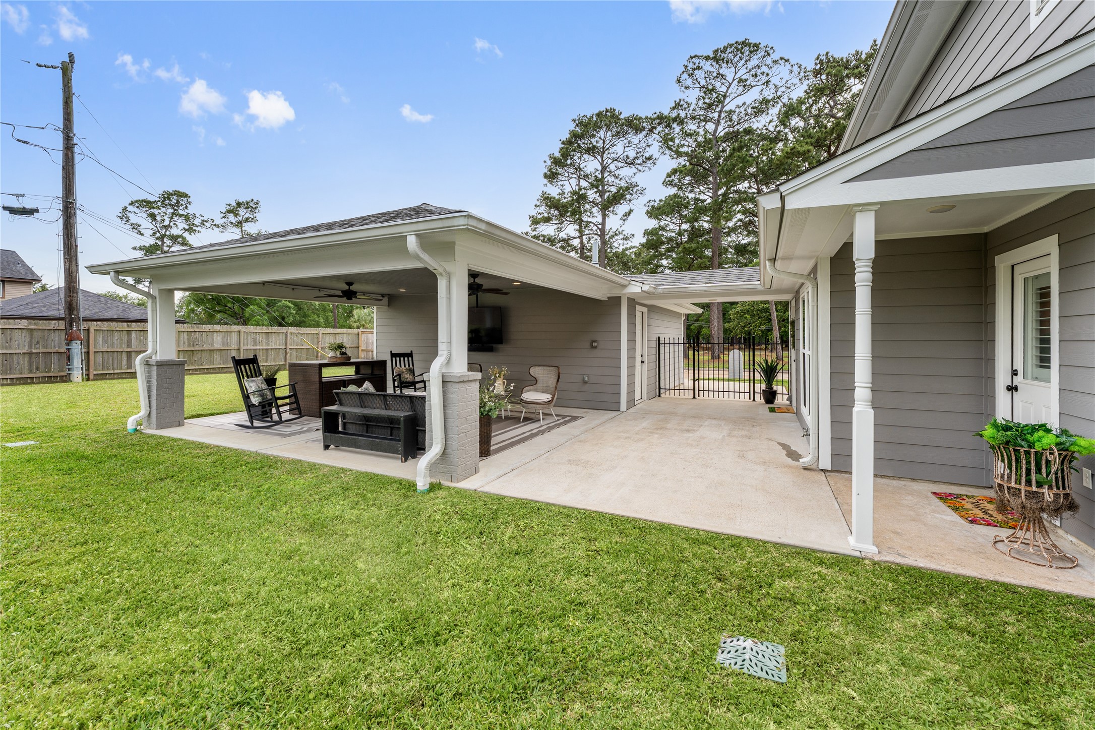 3301 Winter Lane Baytown, TX 77521 - Photo 23 of 28 A spacious backyard with a covered patio, featuring seating areas and a ceiling fan. The area provides a great space for outdoor relaxation and entertaining, surrounded by a well-maintained lawn and a wooden fence for privacy.