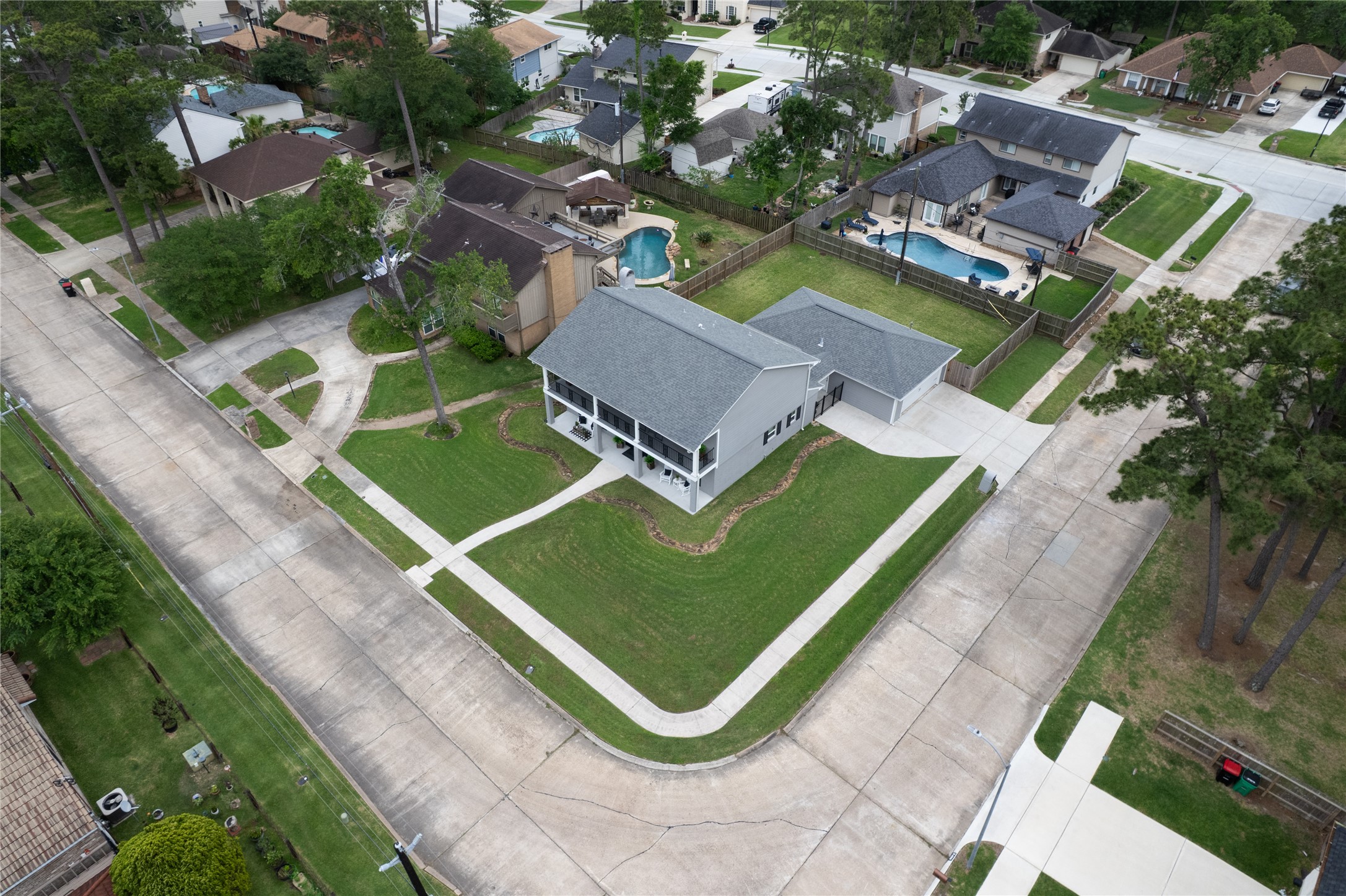 3301 Winter Lane Baytown, TX 77521 - Photo 4 of 28 Aerial view of a spacious, charming two-story home on a corner lot. It features a well-maintained lawn, a large driveway, and a detached garage with ample storage space.