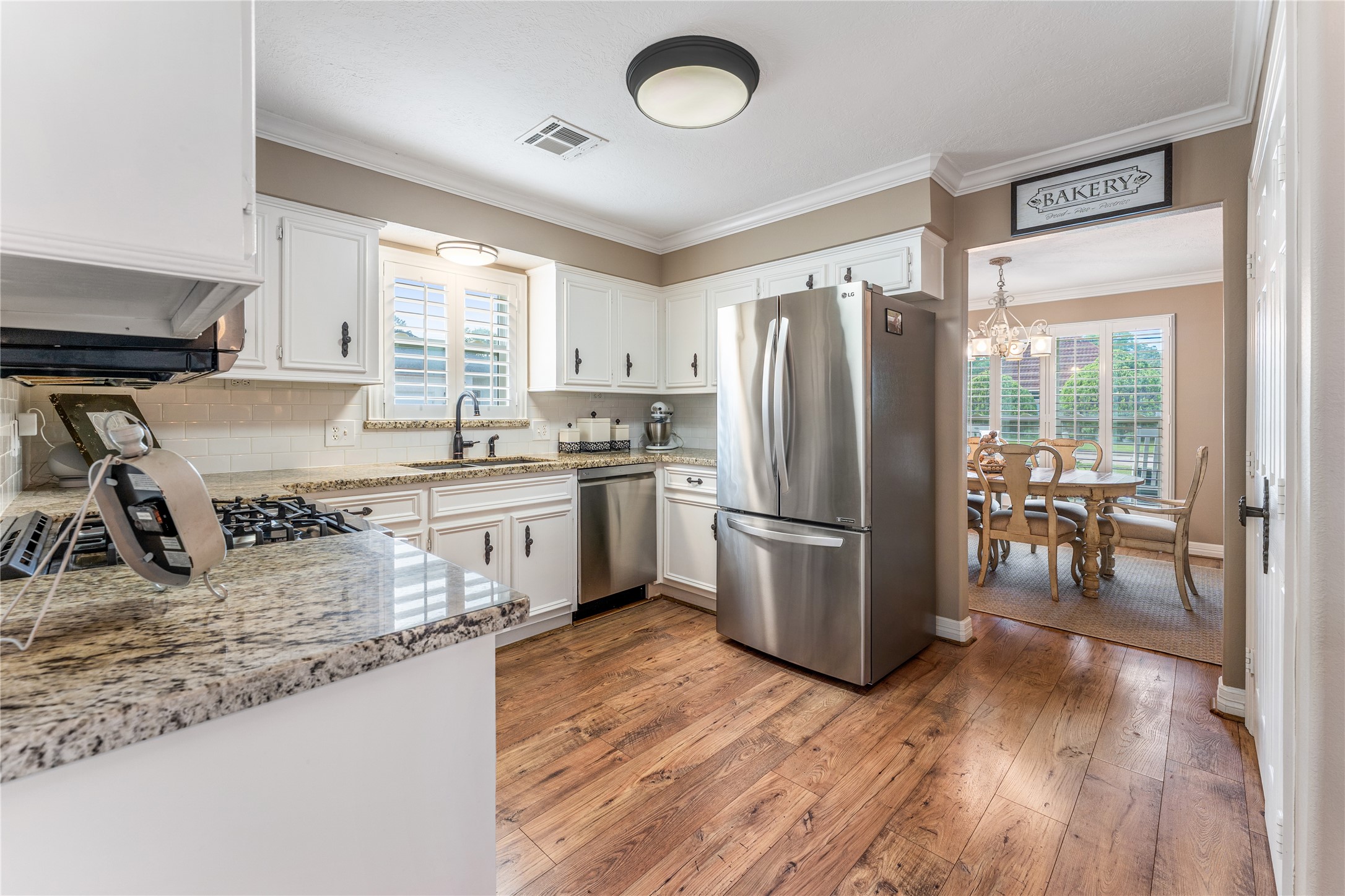 3301 Winter Lane Baytown, TX 77521 - Photo 5 of 28 This kitchen features granite countertops, stainless steel appliances, and white cabinetry. A window above the sink provides natural light, and adjoining dining area offers a cozy space for family meals or game nights.