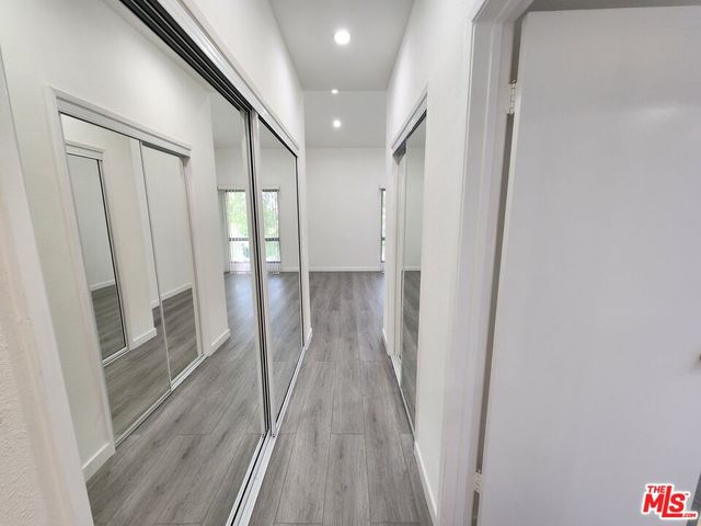 a view of a hallway to a house with wooden floor and windows