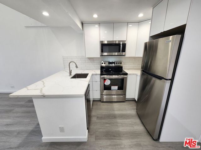a large white kitchen with kitchen island a sink stainless steel appliances and cabinets